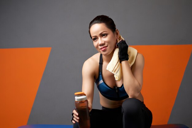 Medium closeup of sporty girl relaxing after exercise with a bottle of water