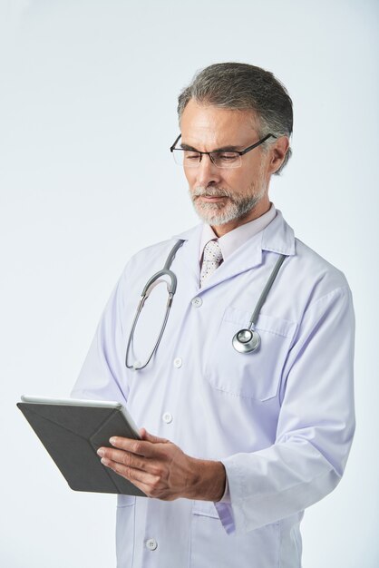 Medium length shot of middle-aged doctor working with digital tablet