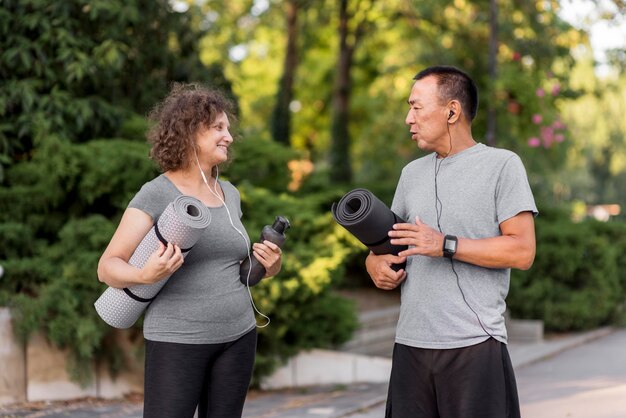 Medium shot adult holding yoga mats