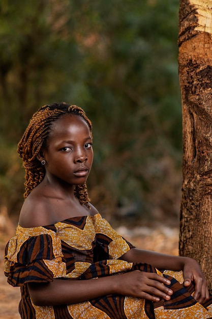 Medium shot african girl posing near tree