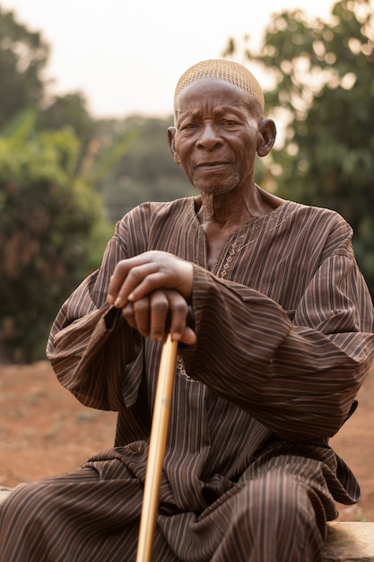 Medium shot african man sitting with cane