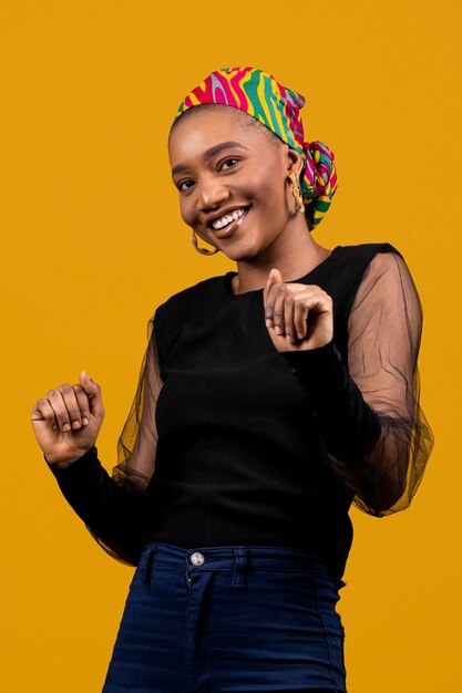 Medium shot african woman dancing in yellow studio