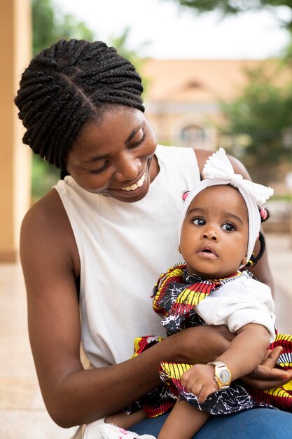 Medium shot african woman holding little girl