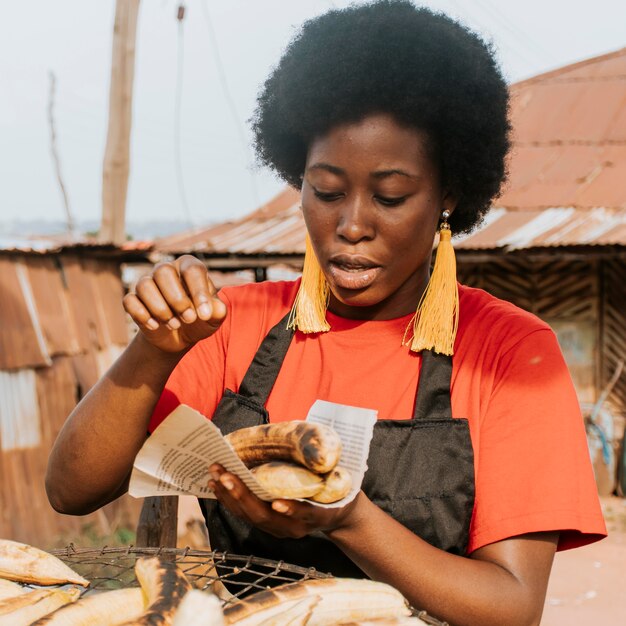 ミディアムショットのアフリカの女性が食べ物を作る