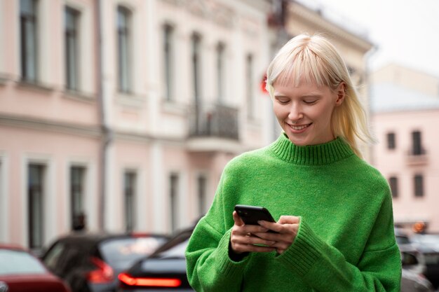 スマートフォンを保持しているミディアムショットのアルビノ女性