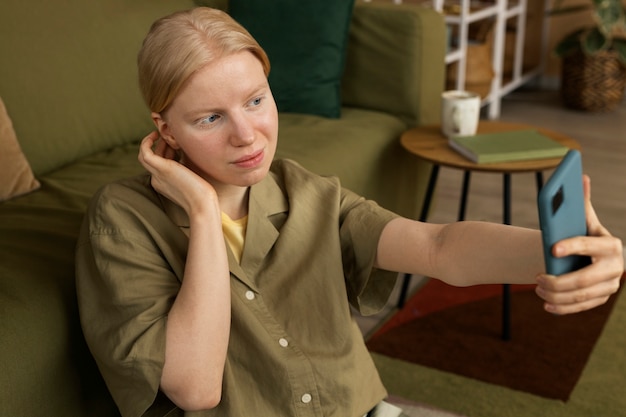 Free photo medium shot albino woman holding smartphone