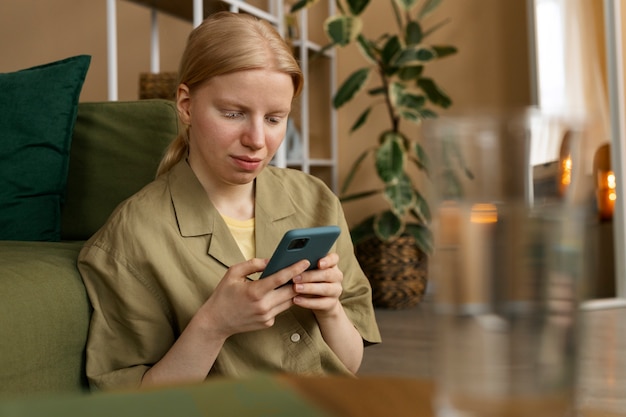 Free photo medium shot albino woman holding smartphone