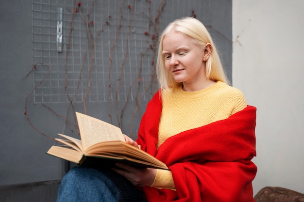 Бесплатное фото Женщина-альбинос среднего роста читает