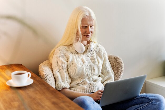 Medium shot albino woman working on laptop