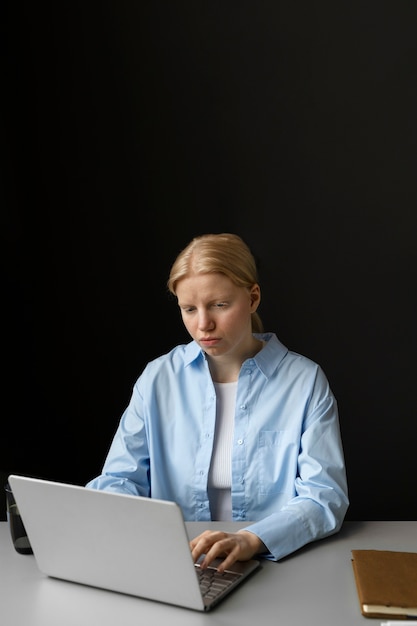 Женщина-альбинос среднего роста, работающая на ноутбуке
