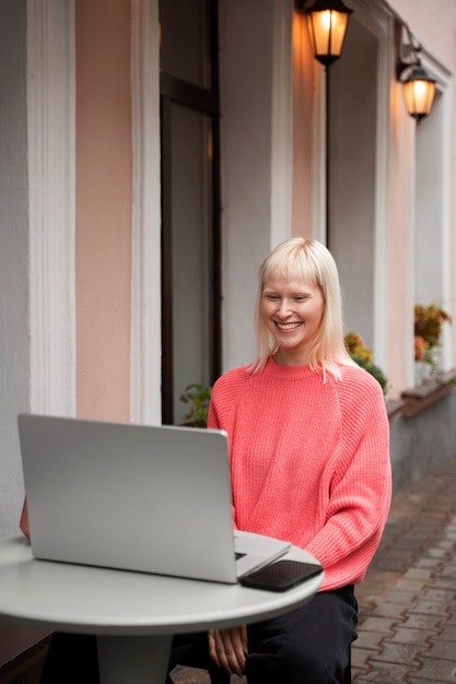 Женщина-альбинос среднего роста, работающая с ноутбуком