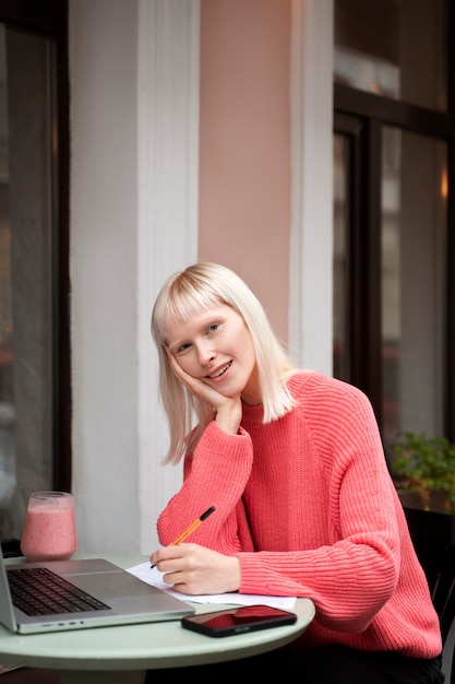 Medium shot albino woman working with laptop