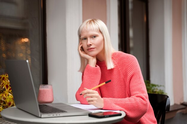 Medium shot albino woman working with laptop