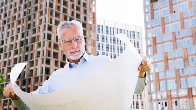 Medium shot architect looking at building plans 