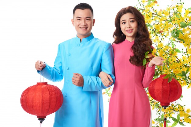 Medium shot of Asian couple in traditional outfits holding red lanterns