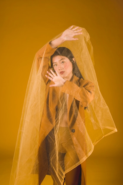 Средний снимок азиатская модель позирует с желтым фоном