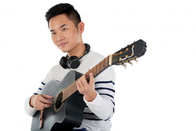 Medium shot of Asian musician composing melody on guitar