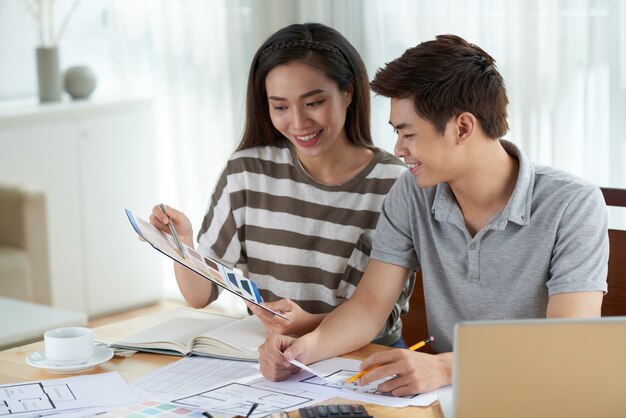 Medium shot of Asian woman sharing creative ideas on home design with husband