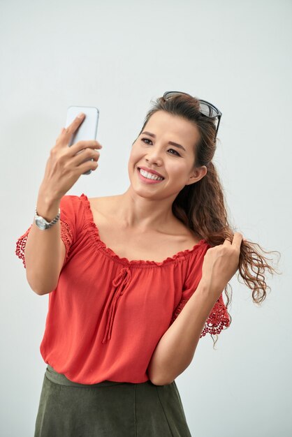 Medium shot of attractive lady taking a selfie with a smartphone