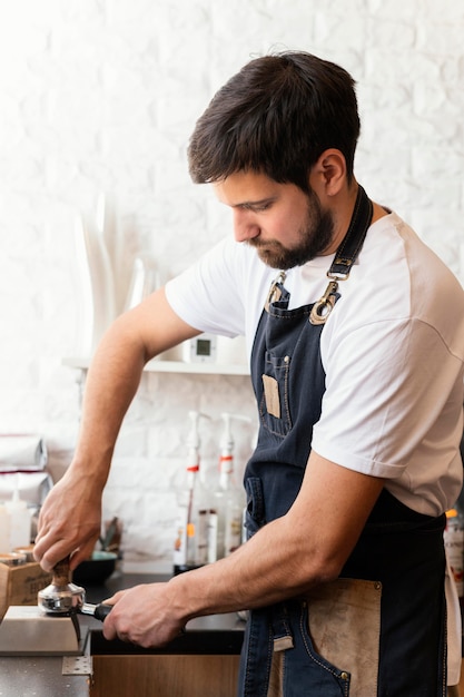 Foto gratuita barista a tiro medio che macina caffè