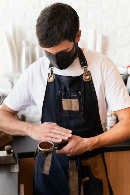 Foto gratuita barista a tiro medio con maschera funzionante