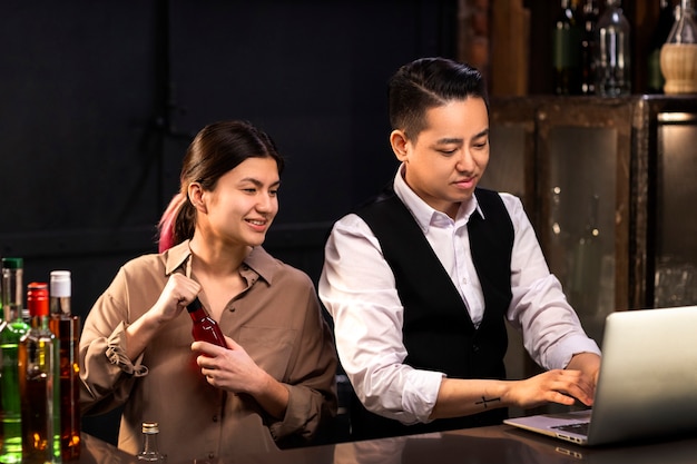 Free photo medium shot bartenders working with laptop