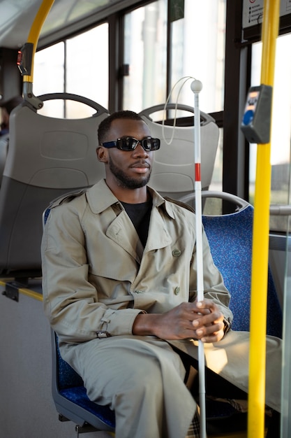 Free photo medium shot blind man traveling by bus with cane