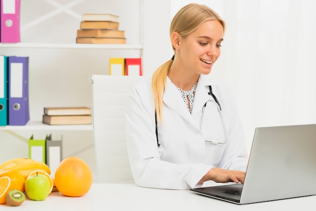 Free photo medium shot blonde doctor with laptop