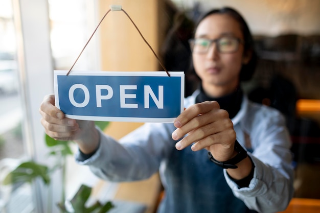 Medium shot blurry man arranging open sign