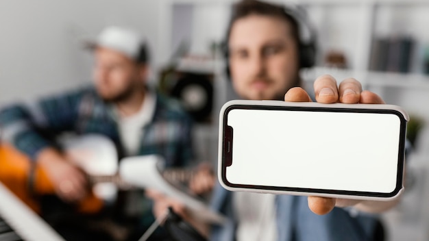 Uomo sfocato del colpo medio che tiene smartphone