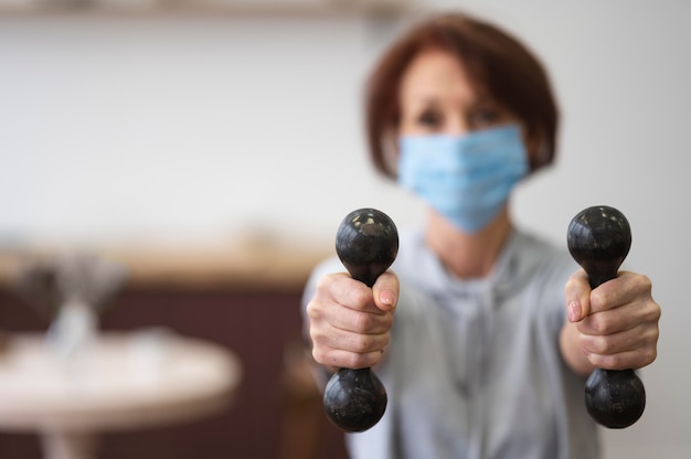 Medium shot blurry woman holding dumbbells