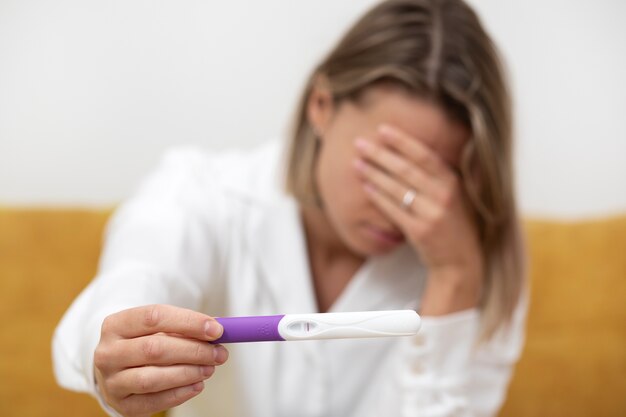 medium shot blurry woman holding pregnancy test