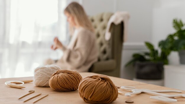 Medium shot blurry woman knitting indoors