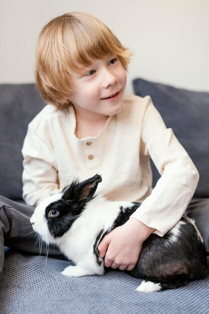 Средний выстрел мальчик держит кролика
