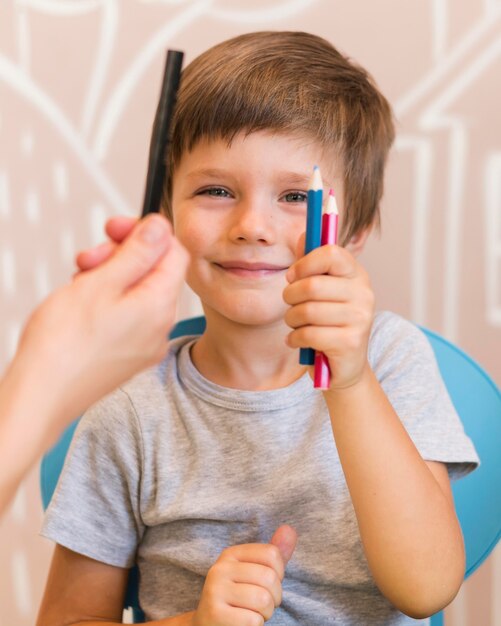 Medium shot boy holding crayons