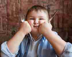 Free photo medium shot boy holding cutlery