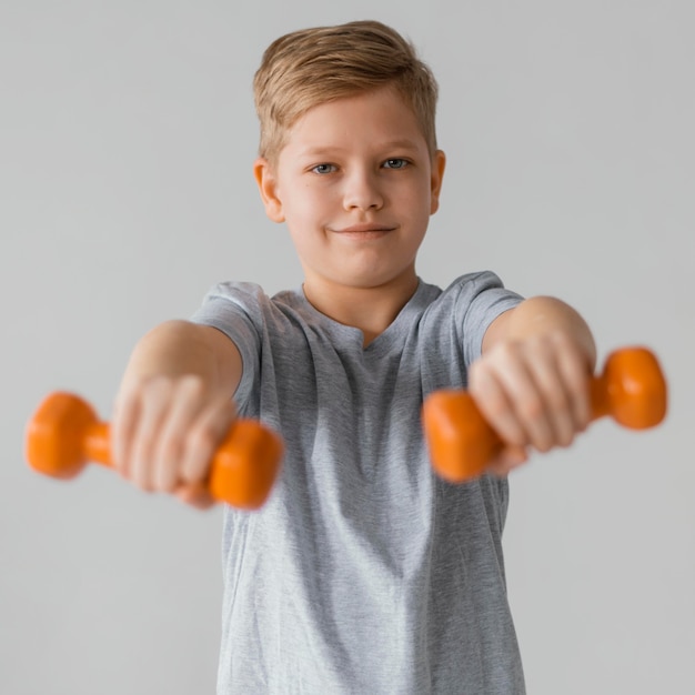 Free photo medium shot boy holding dumbbells