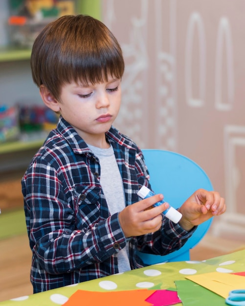 Medium shot boy holding glue stick