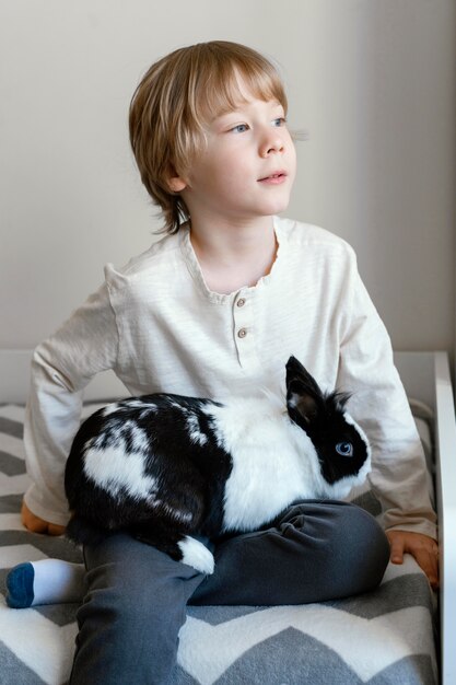 Средний выстрел мальчика, держащего кролика