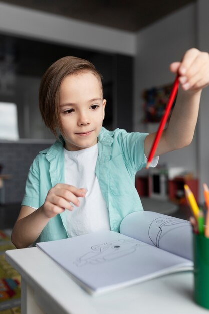 Medium shot boy holding red crayon