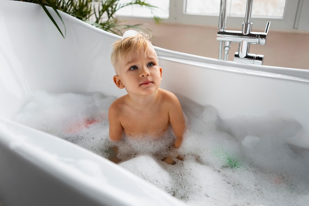 Бесплатное фото Мальчик среднего роста играет в ванне