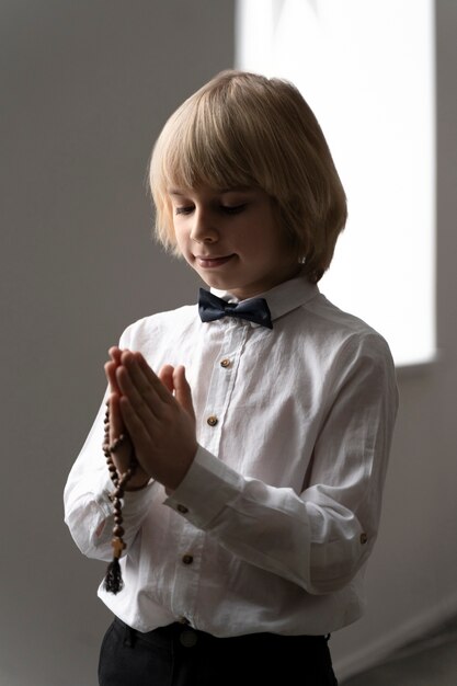 十字架で祈るミディアムショットの少年