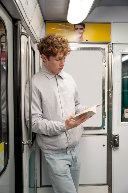 Free photo medium shot boy reading in public transport