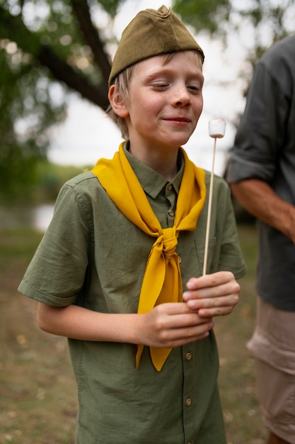 Foto gratuita boy scout di tiro medio con marshmallow