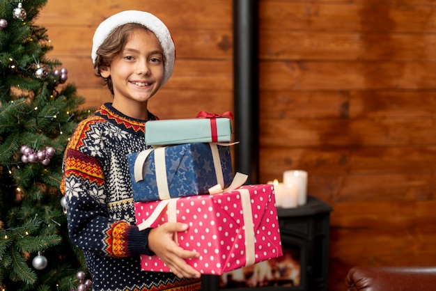 Medium shot boy with gifts near christmas tree