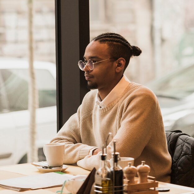 Medium shot boy with glasses sitting at a table