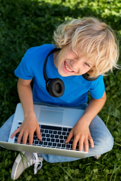 ノートパソコンとヘッドフォンを持ったミディアムショットの少年