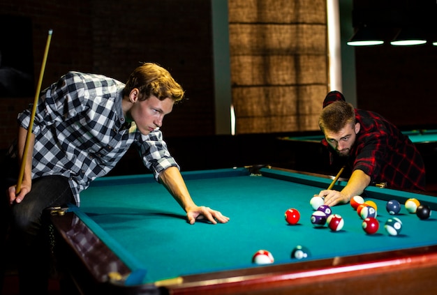 Medium shot boys playing billiard together 