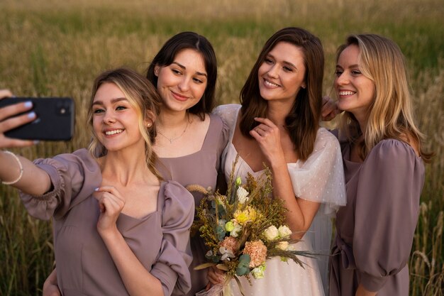 Medium shot bride and bridesmaids taking selfie
