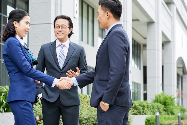 Free photo medium shot of business people shaking hands outdoors